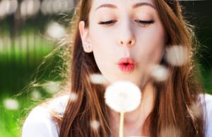 Girl blowing seeds of a dandelion flower Girl blowing seeds of a dandelion flower